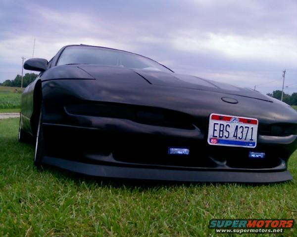 Black 1993 Ford Probe with a license plate reading EBS 4371, parked on grass