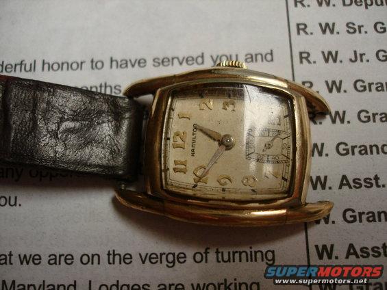 Gold-toned Hamilton watch with a black leather strap, face showing Arabic numerals and a subdial