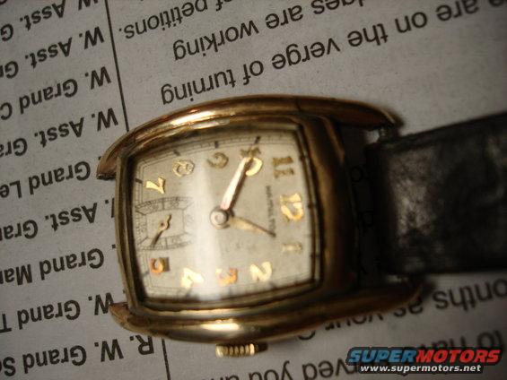 Gold watch with black band on newspaper