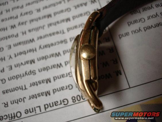 Close-up of a gold watch with a leather band, resting on a document