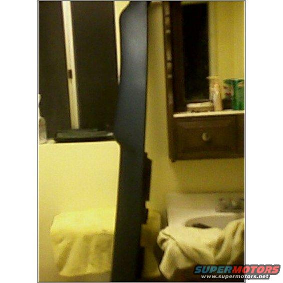Dark blue trim piece leaning against a yellow wall, with a sink and cabinet in the background