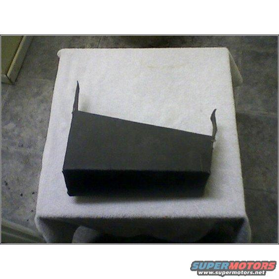 Black plastic part with angled top and two small tabs on the right side, sitting on a white cloth