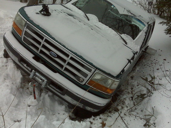 Green Ford Bronco stuck in snow, front view with winch
