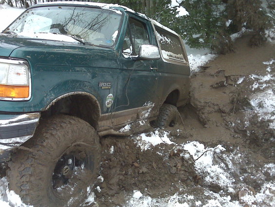 Green 1996 Ford Bronco stuck in mud and snow, front 3/4 view