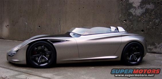 Silver concept car with black accents and wheels parked against a concrete wall
