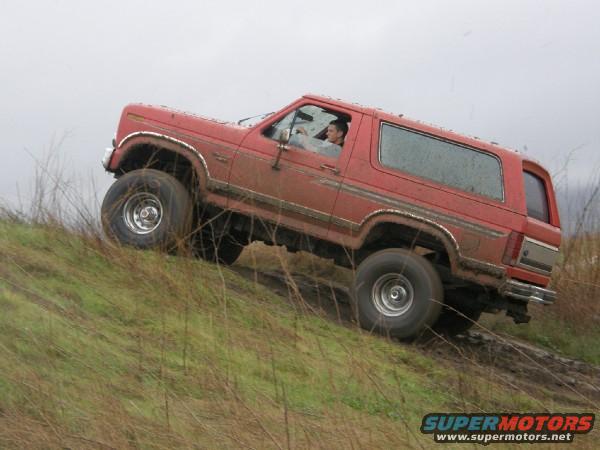 red SUV driving up muddy hill, driver visible