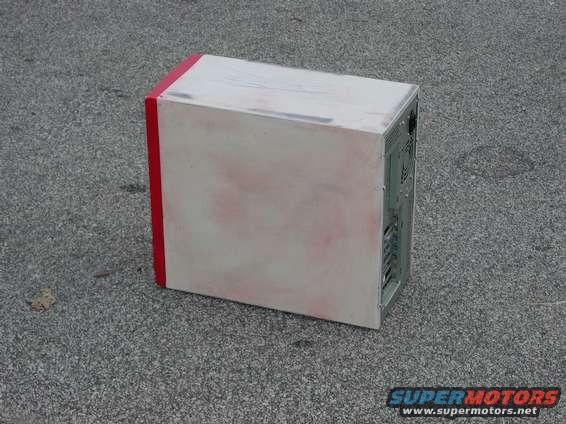 Computer tower with red trim and white casing on asphalt