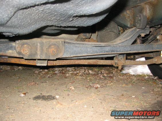 Underside of a car showing rusty suspension components and exhaust