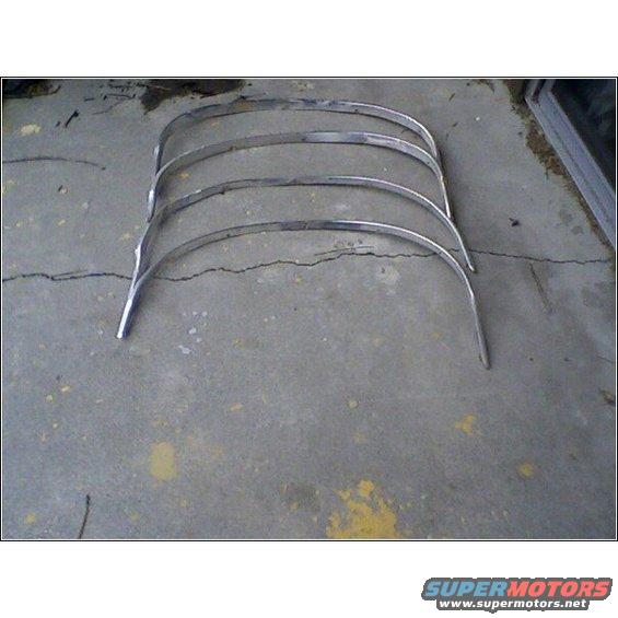 Four curved chrome trim pieces with visible wear, lying on a cracked concrete floor