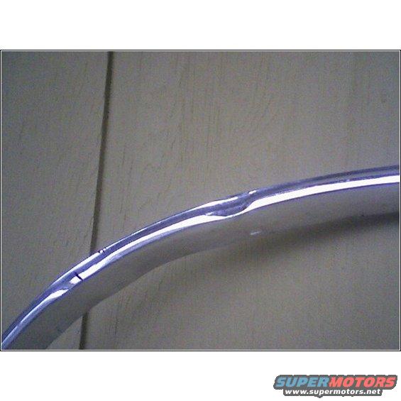 Curved chrome trim piece with a dent and scratch