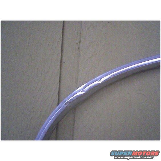 Dented chrome trim piece against a wall