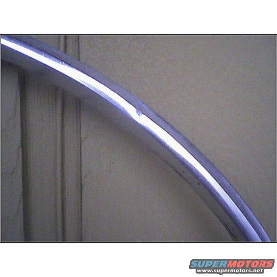 Close-up of a curved chrome trim piece with a dent