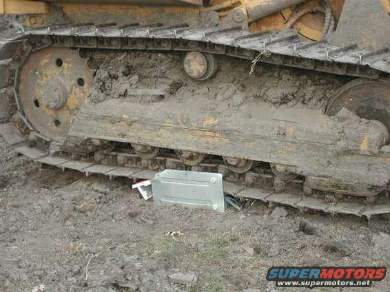 Close-up of muddy bulldozer tracks with a silver metal object on the ground
