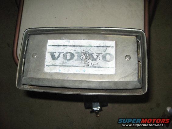 Close-up of a Volvo emblem on a rectangular metal plate, showing wear and some scratches