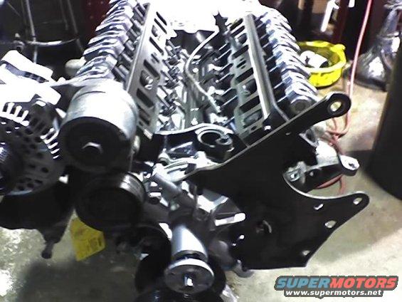 Engine block with alternator, pulleys, and mounting bracket. Yellow tag visible