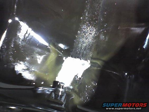 Close-up of a fuel filler neck with some debris around it. Supermotors.net logo in corner