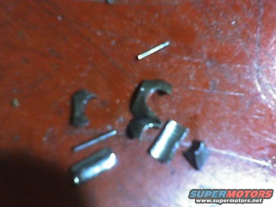 Several small, dark metal pieces and pins scattered on a red surface