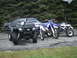 1996 Ford Bronco - A collection of vehicles including a four-wheeler, two dirt bikes, and a car are parked on pavement.