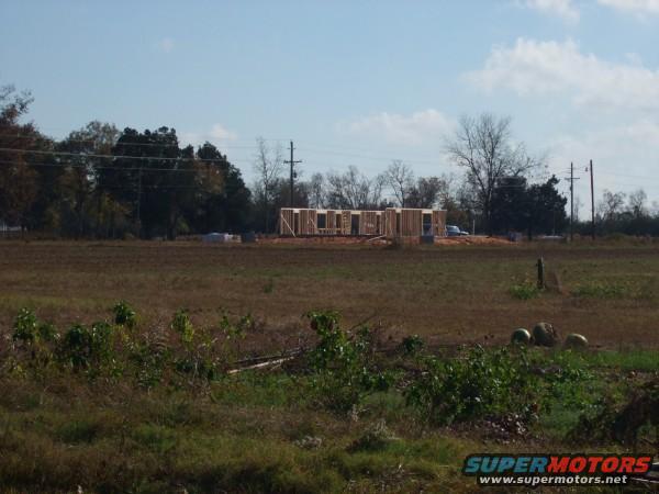 Construction site with house framing and a distant white vehicle