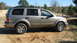 2004 Dodge Durango - This tan 2004 Dodge Durango SUV is parked on a dirt road with trees in the background.