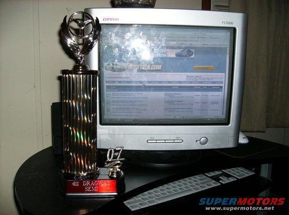 Computer monitor showing ProbeTalk.com forum, trophy with steering wheel emblem, and keyboard