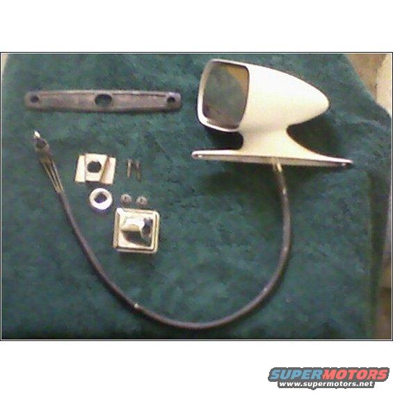 White car side mirror assembly with mounting bracket, cable, and screws laid out on dark green fabric
