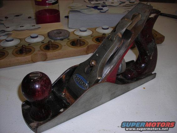 Craftsman hand plane on a workbench with a wooden organizer holding small parts