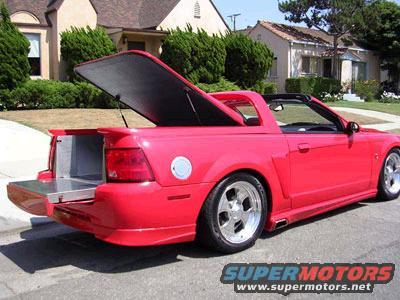 Red coupe utility vehicle with open tailgate and bed cover, rear 3/4 view