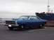 1966 Ford Fairlane - This blue 1966 Ford Fairlane coupe features a prominent hood scoop and is parked near a large ship.