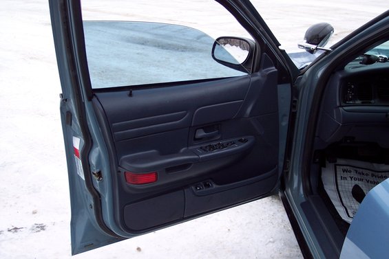 Blue car interior with open driver's door, showing door panel, window controls, and floor mat
