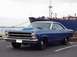1966 Ford Fairlane - A blue 1966 Ford Fairlane coupe, a prominent hood scoop, is parked in front of a large cargo ship.