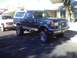 1991 Ford Bronco - Lifted 1991 Ford Bronco parked on a residential street next to a white pickup truck.