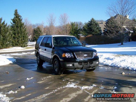 Black and silver Ford Expedition parked on a wet driveway with snow on the sides