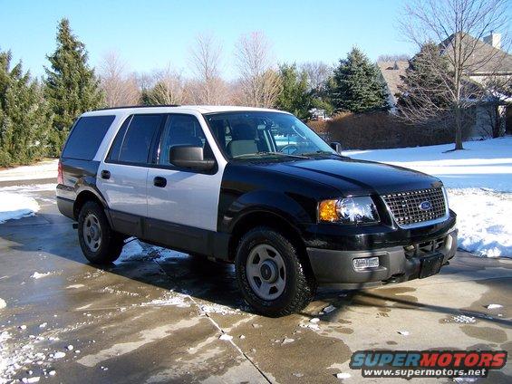 Front-right view of a black and white 2004 Ford Expedition parked on a wet driveway with snow patches