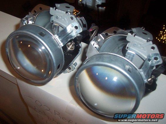 Two disassembled headlight assemblies with clear lenses and metal housings