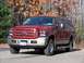 2005 Ford Excursion - This 2005 Ford Excursion is shown in a front 3/4 view with a red body and tan lower trim. The license plate reads 'GOT3SONS'.