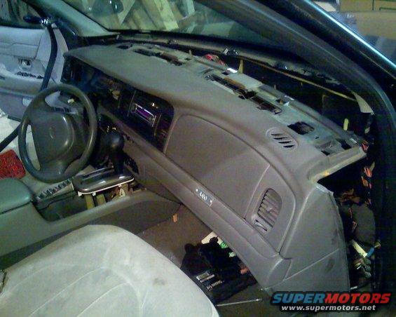 car dashboard with steering wheel and center console removed, showing wiring and internal components