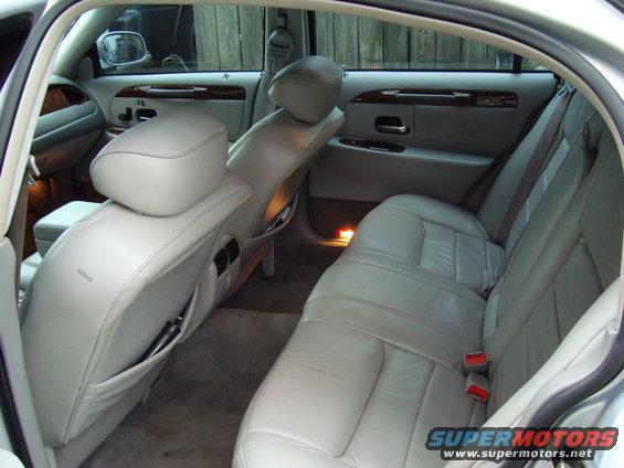 Interior view of a 2002 Lincoln Town Car showing front and rear leather seats, door panels, and wood trim