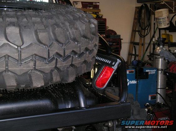 Spare tire mounted on the back of a vehicle, with a red taillight visible
