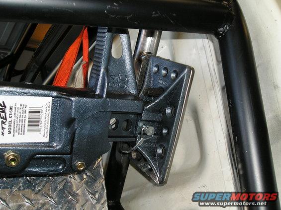 Close-up of a Hi-Lift XT-605 jack mount attached to a roll cage with an orange strap visible