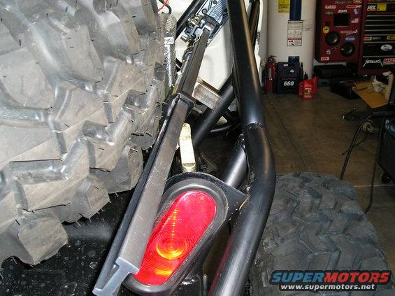 Spare tire and red taillight on a modified vehicle with a roll cage