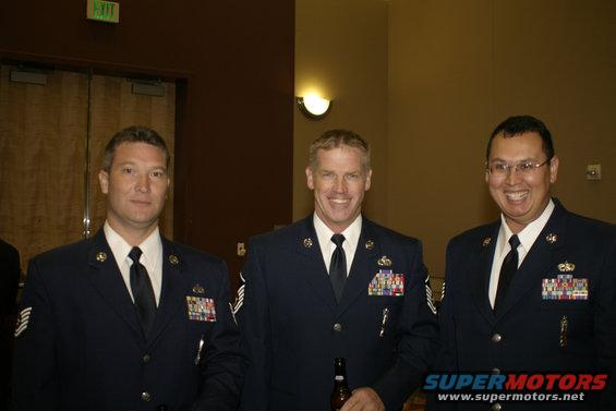 Three men in dark blue uniforms with ties and medals