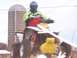 2001 Polaris TRAIL BLAZER - A rider on a yellow and white ATV is captured in motion near a silo, with a watermark indicating Supermotors.net.