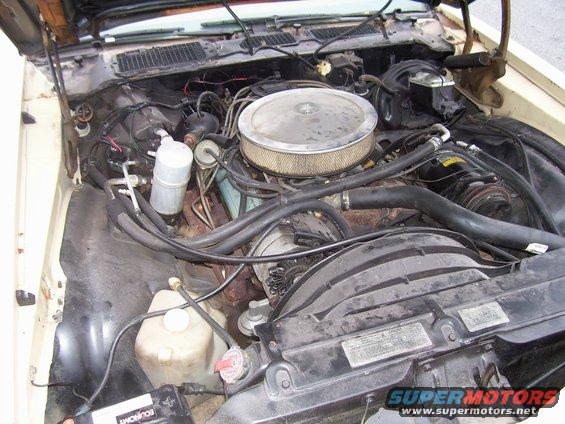 Engine bay with V8 engine, air cleaner, radiator, and battery visible. Some hoses and wiring are present