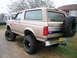 1996 Ford Bronco - This lifted Ford Bronco is parked on a gravel driveway with grass and houses in the background.