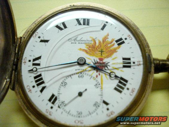 Close-up of an Admiral Non Magnetic pocket watch face with Roman numerals and a Sacred Heart illustration