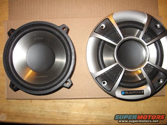 Two Blaupunkt car speakers, one with a silver grille, on a cardboard surface