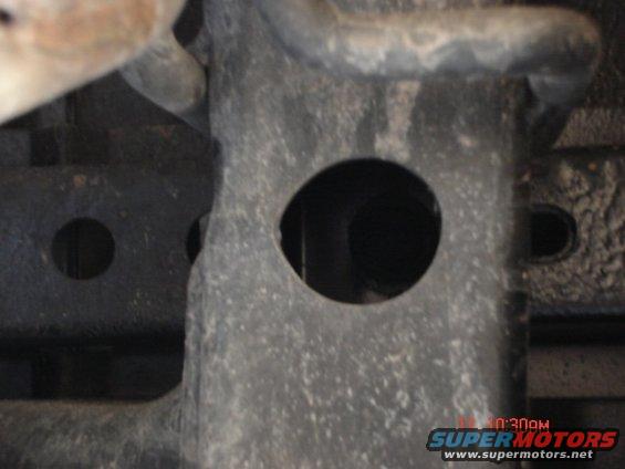Close-up of vehicle frame showing two circular holes and some metal tubing