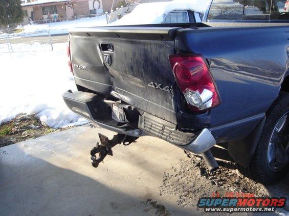 Pickup truck's rear bumper and tailgate are smashed in. A trailer hitch hangs loose