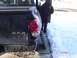 1981 Ford Bronco - A dark blue pickup truck shows damage to its rear, including a broken taillight and bumper, with a person standing nearby in a snowy enviro…
